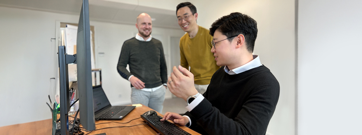 Yu Seok Choi interacts with Q ENERGY Solutions colleagues at his desk.
