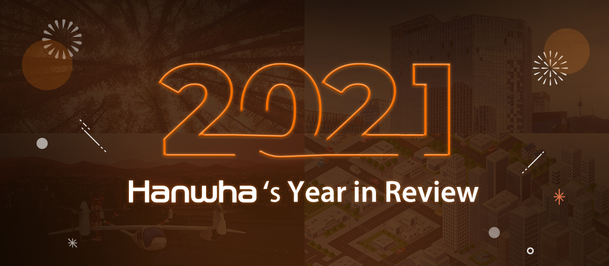 '2021 Hanwha's Year in Review' text and fireworks elements are placed over four images of the forest, Hanwha Seoul Headquarters, an air taxi Butterfly, and an illustration of Hanwha Techwin's smart city