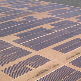 An aerial view of multiple Hanwha solar PV panels installed across a sweeping plain with green fields in the background
