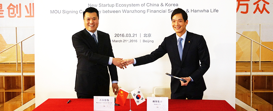 Hanwha's Dong Won Kim and Yida Group's CEO pose for a photograph after signing an agreement to develop promising fintech companies