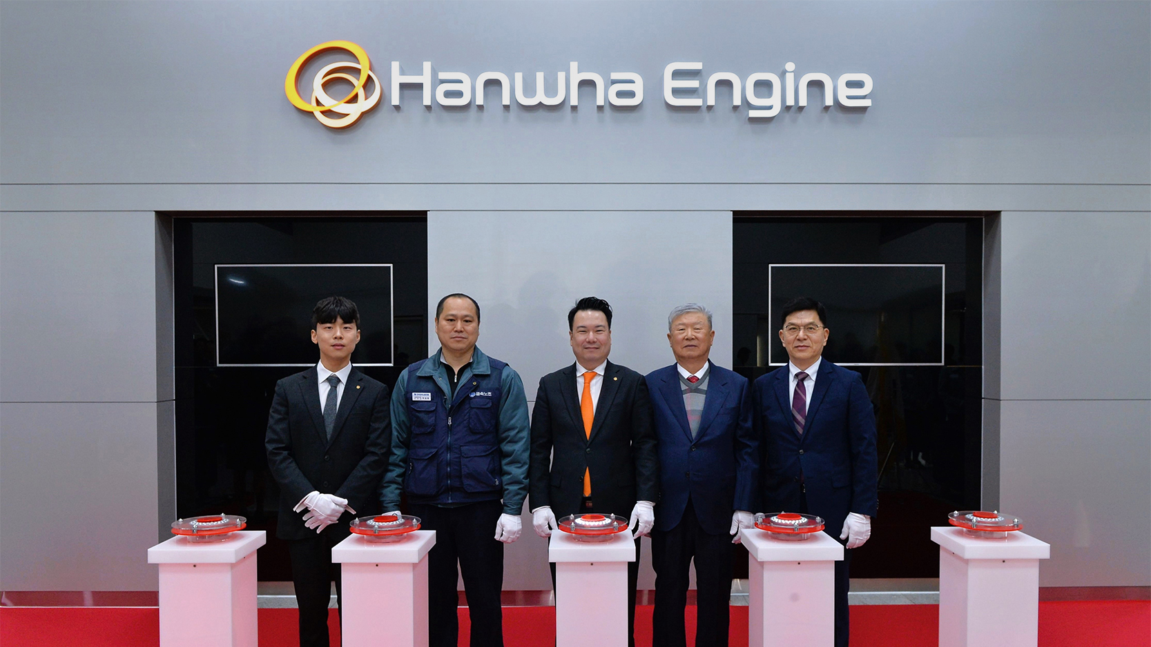 Five Hanwha Engine representatives pose for a photo in front of the company logo at an event celebrating its launch.