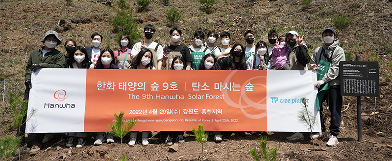 Participants hold up a banner commemorating the opening of Hanwha’s ninth Solar Forest in Gangwon-do, South Korea.