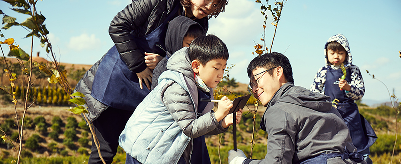 A young boy is writing a message for future visitors next to the oak tree sapling he had just planted at Hanwha Solar Forest No. 7