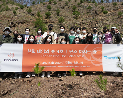 Participants hold up a banner commemorating the opening of Hanwha’s ninth Solar Forest in Gangwon-do, South Korea.