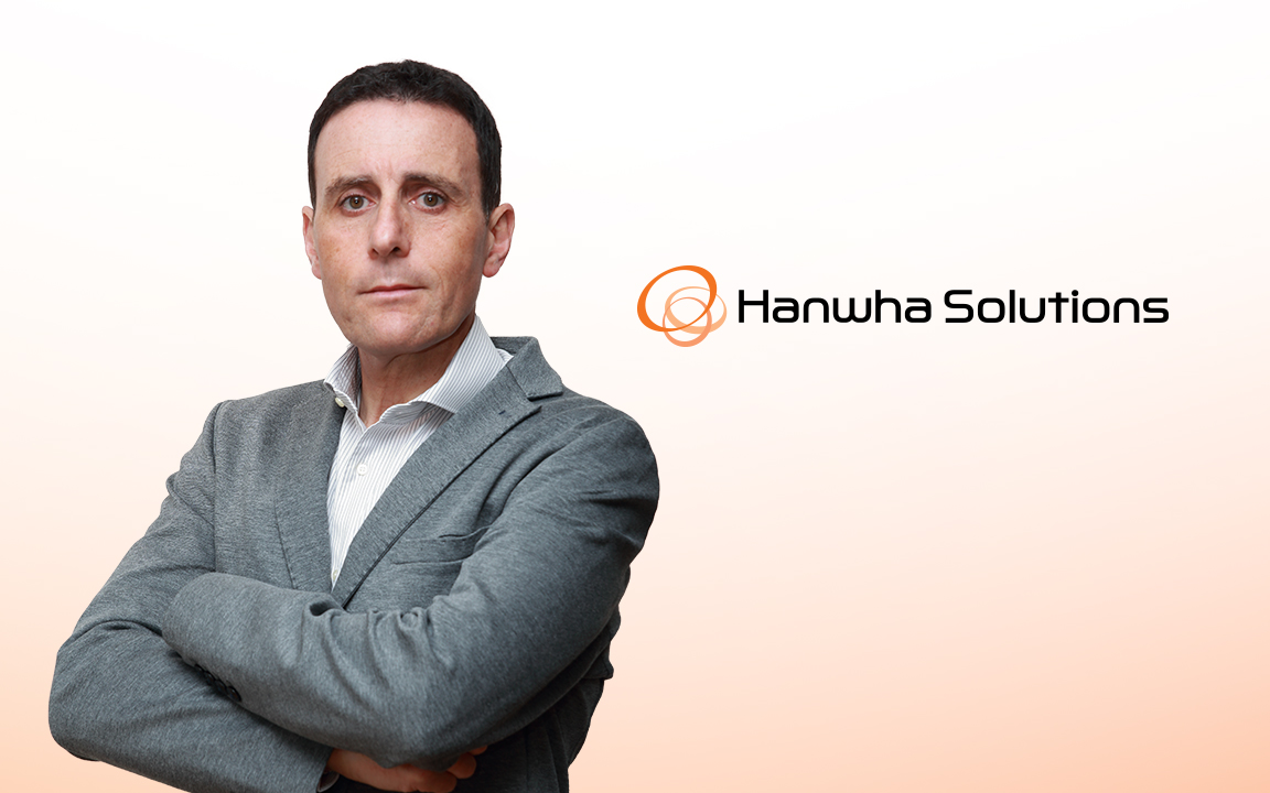 Carlo Scarlata, CEO of Hanwha’s Wire & Cable Division, in a gray suit, standing against a white wall with arms crossed.