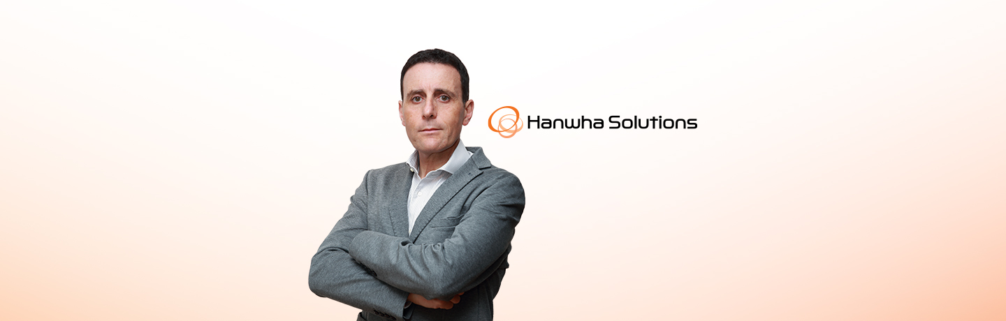 Carlo Scarlata, CEO of Hanwha’s Wire & Cable Division, in a gray suit, standing against a white wall with arms crossed.