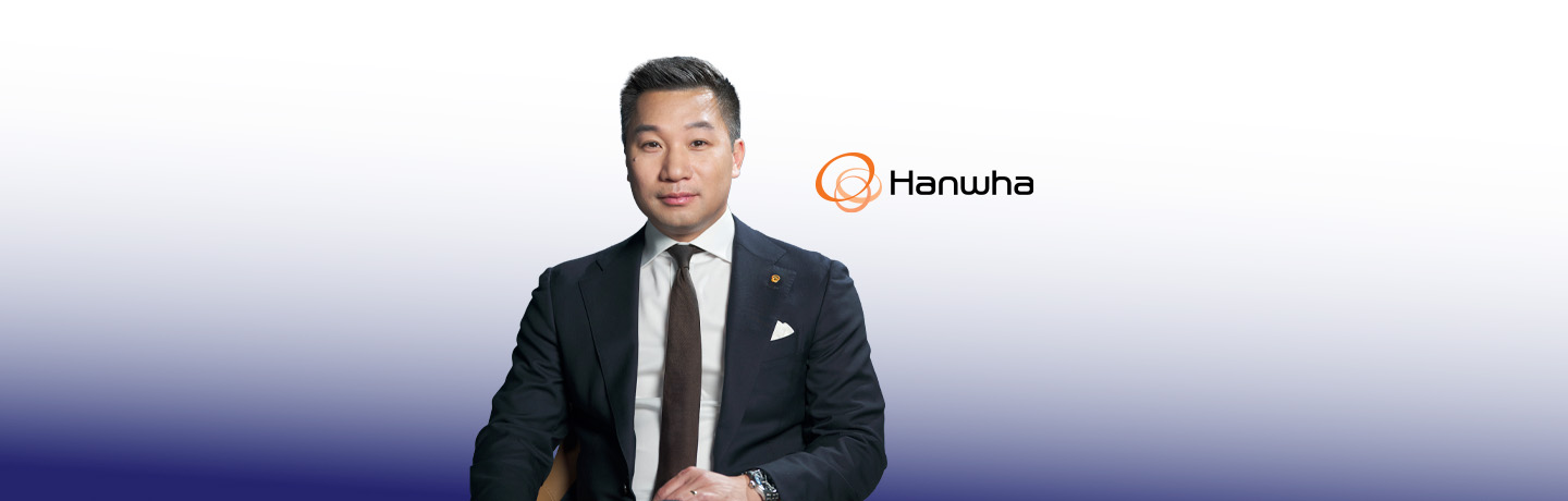 Alex Wong sits in a chair and looks at the camera in front of a blue background.