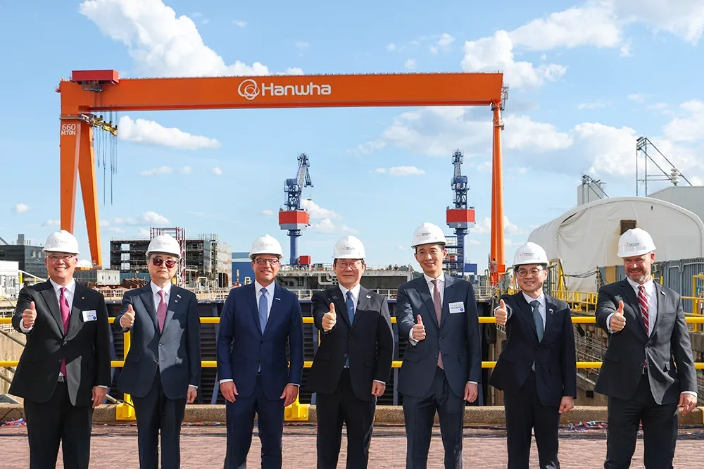 Seven delegates from Hanwha Group and the US government pose with a thumbs-up sign at the shipyard.