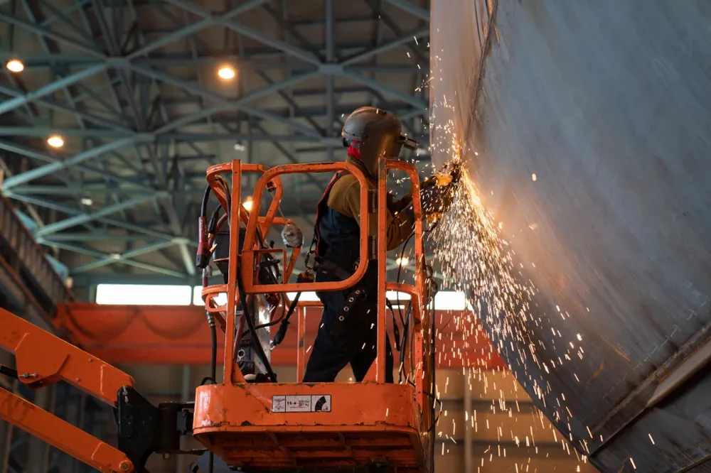 A worker on a boom lift platform welds a ship at Hanwha Philly Shipyard. 