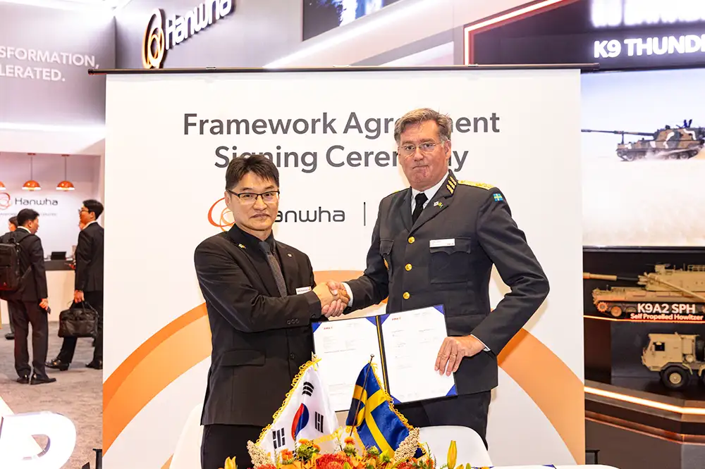 Hanwha Aerospace’s Billy Boo-Hwan Lee and FMV’s Jonas Lotsne shake hands after signing an MCS agreement at AUSA 2025.