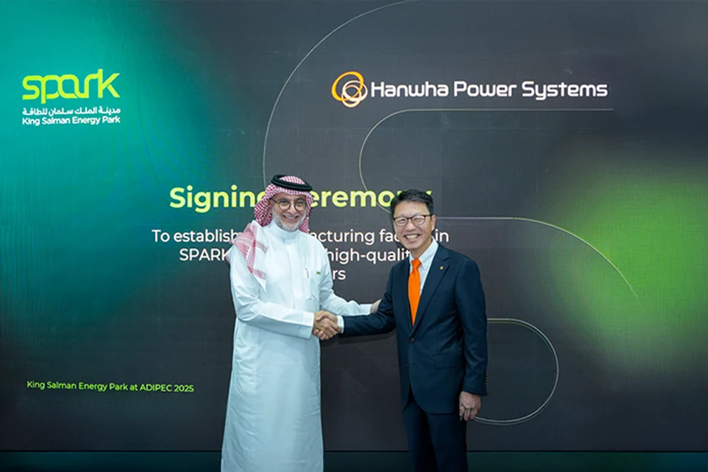 Executives from Hanwha Power Systems and SPARK shake hands after signing a land lease agreement at ADIPEC 2025