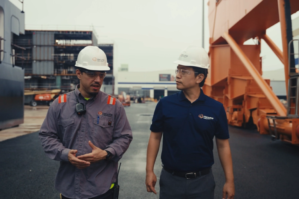 A dual graphic with two men with hard hats walking through a construction site and large monitors at the Smart Yard Operation Center. 