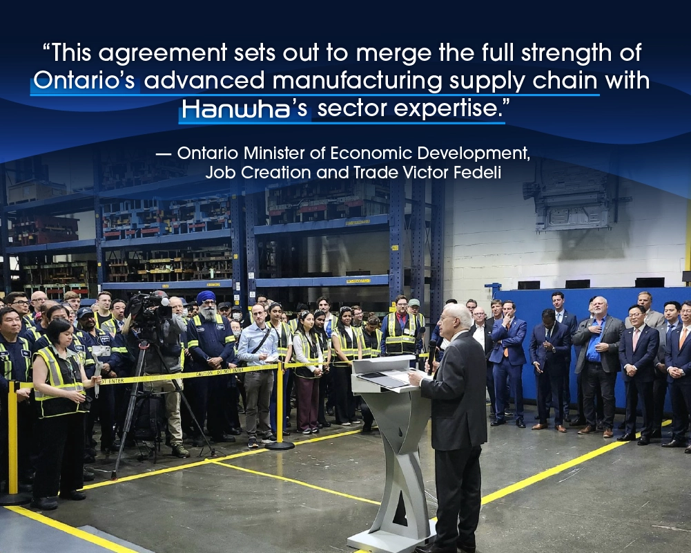 Minister Victor Fedeli addresses media in a warehouse.