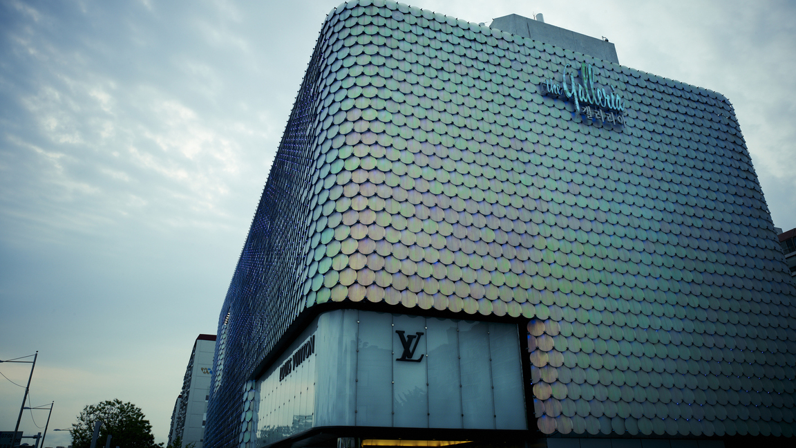 Hanwha Galleria Gwanggyo in Suwon, Korea, seen against the night sky with flashes of green and pink in the sky