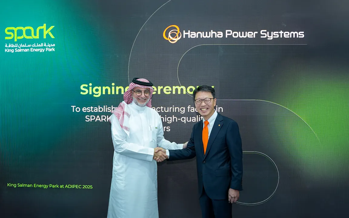 Executives from Hanwha Power Systems and SPARK shake hands after signing a land lease agreement at ADIPEC 2025