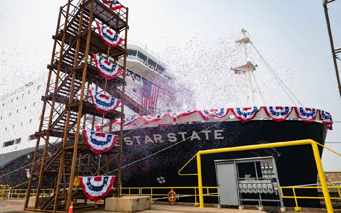 A large vessel with LONE STAR STATE written on the side, with confetti falling and Americana flags draped over the side.